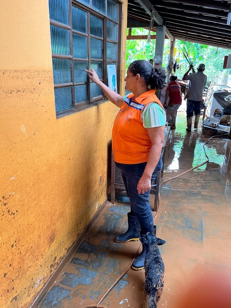 agente de defesa civil em monteiro lobato calcula altura de alagamento em parede de casa. 